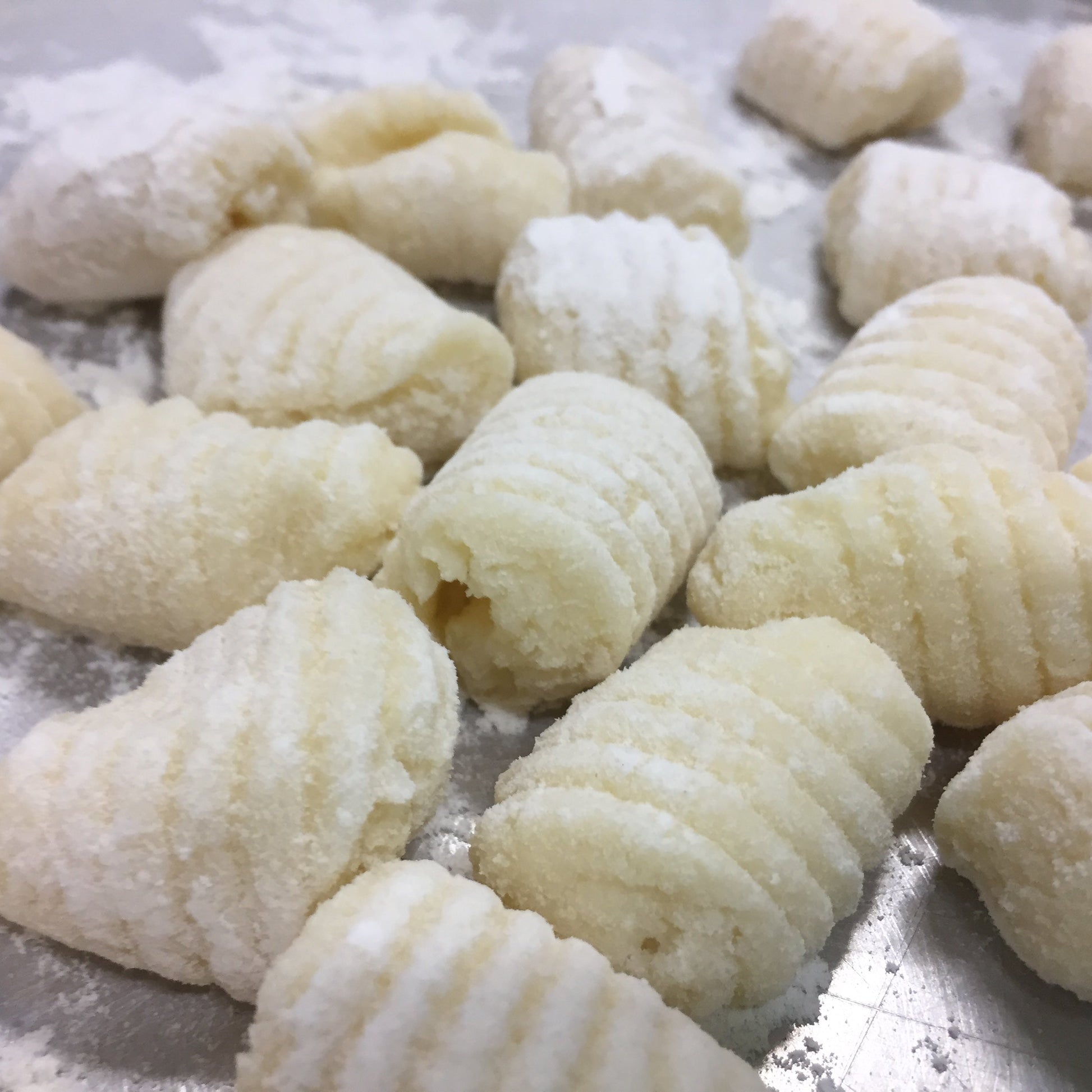 Raw gnocchi on a floured surface. Learn how to make gnocchi perfectly evertime with this cooking class.